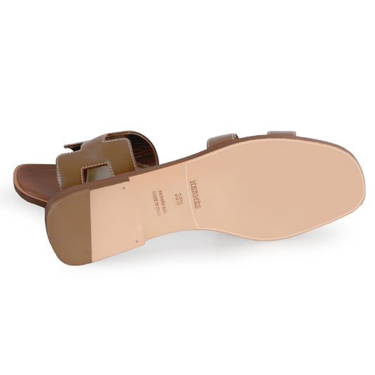 Brown sandal featuring a tan leather sole and an iconic "H" shaped upper, reminiscent of the Hermès Oran Sandal Sole Guard 3 Pack.
