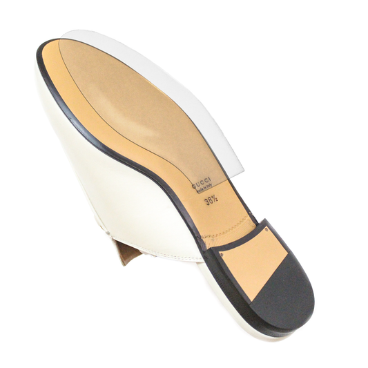 The underside of a white heeled shoe displays its intricate design, enhanced with durable vinyl polymer protectors from the Gucci Princetown Sole Guard 3 Pack.