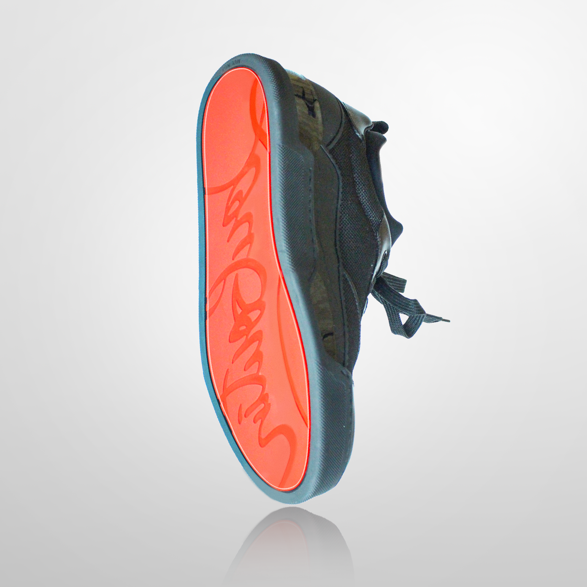 The Louboutin Sneaker Aurelien Rankick Sole Guard, a black sneaker with an orange sole and red signature design, is displayed on a reflective surface. It features stylish vinyl polymer details for durability and flair.