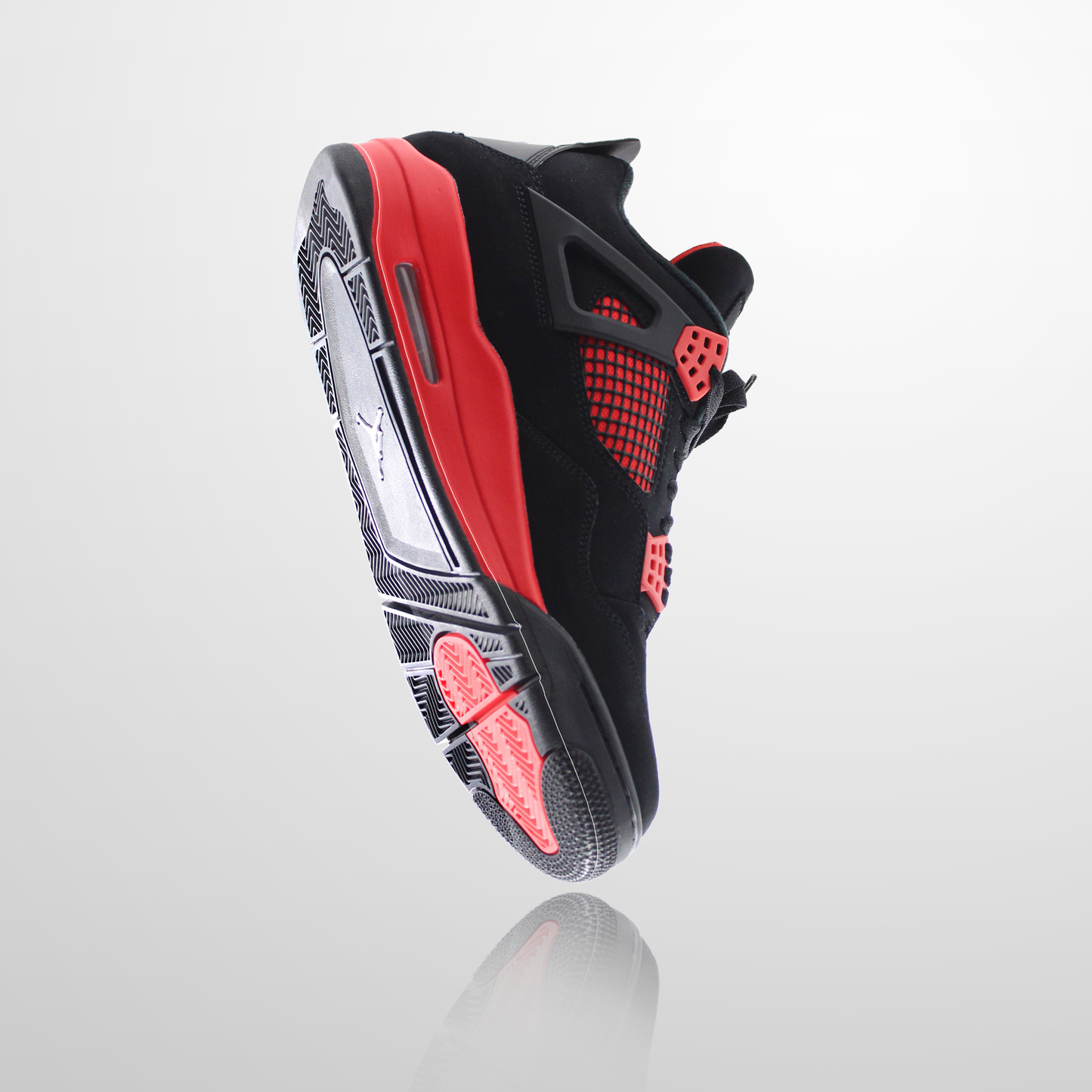 The Jordan 4 Sole Guard sneaker features a black and red design with a sleek white sole, shown mid-air on a light gray background.