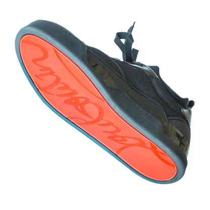 The sneaker, viewed from below, boasts a black upper with a vibrant orange sole and cursive text. Its vinyl polymer accents enhance durability, making it perfect for those wanting the Louboutin Aurelien Rankick style with long-lasting quality.